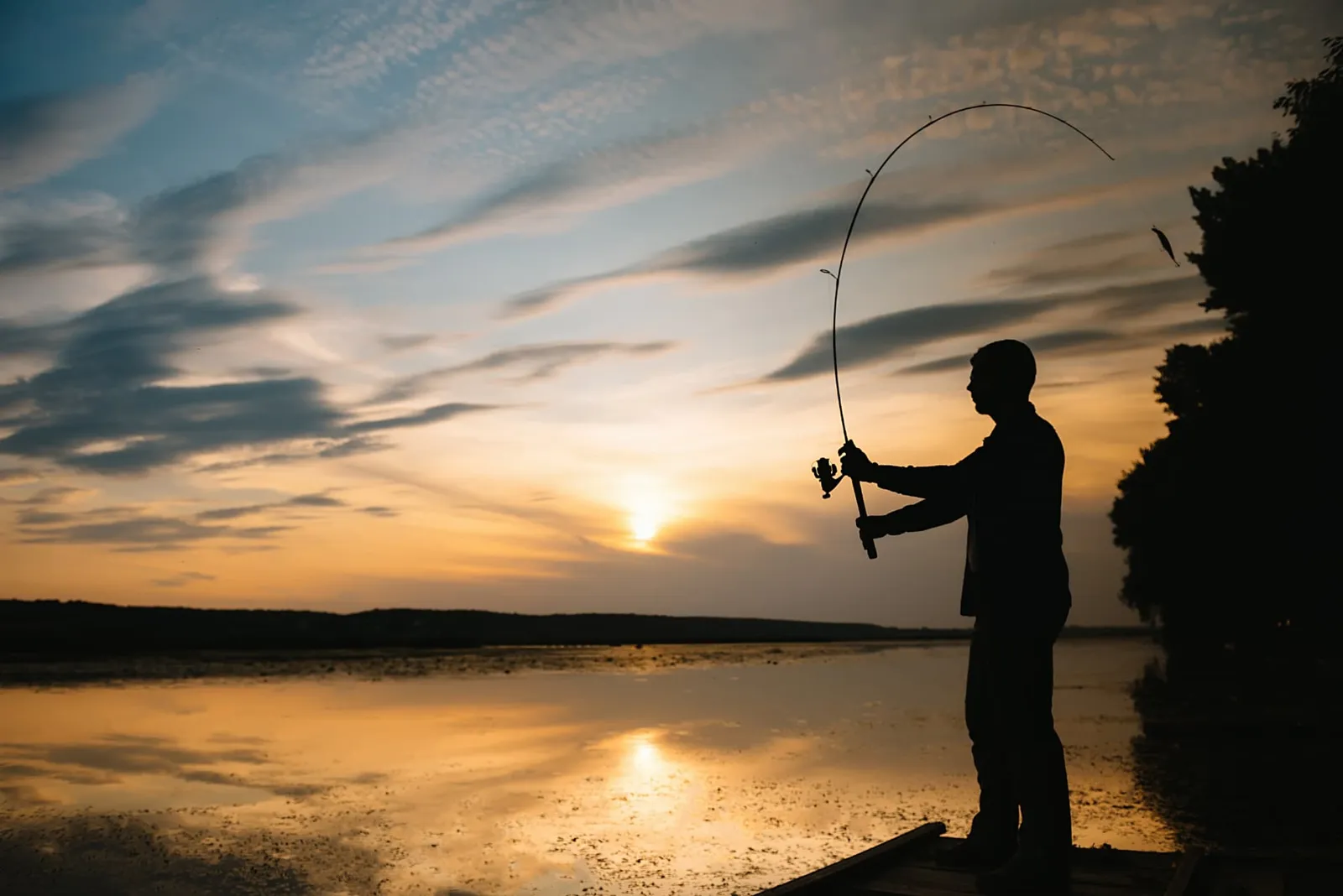 Angler on a dock casting a lure at sunset