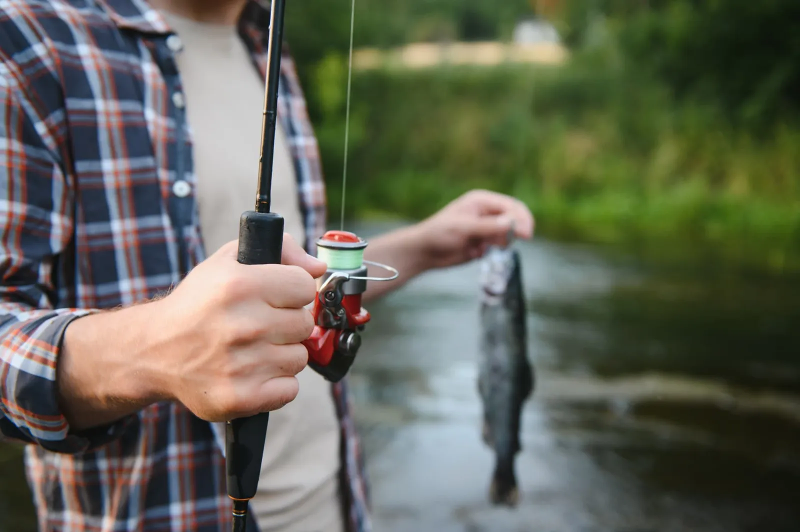 Angler with a spinning rod holding a freshly caught trout