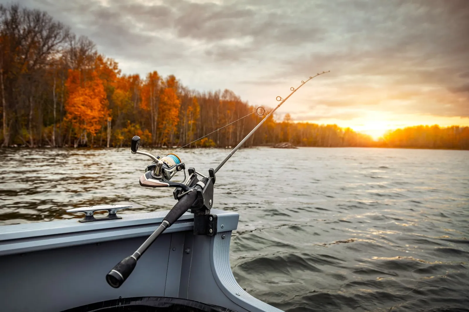 Spinning rod in a boat holder on an autumn lake at sunrise