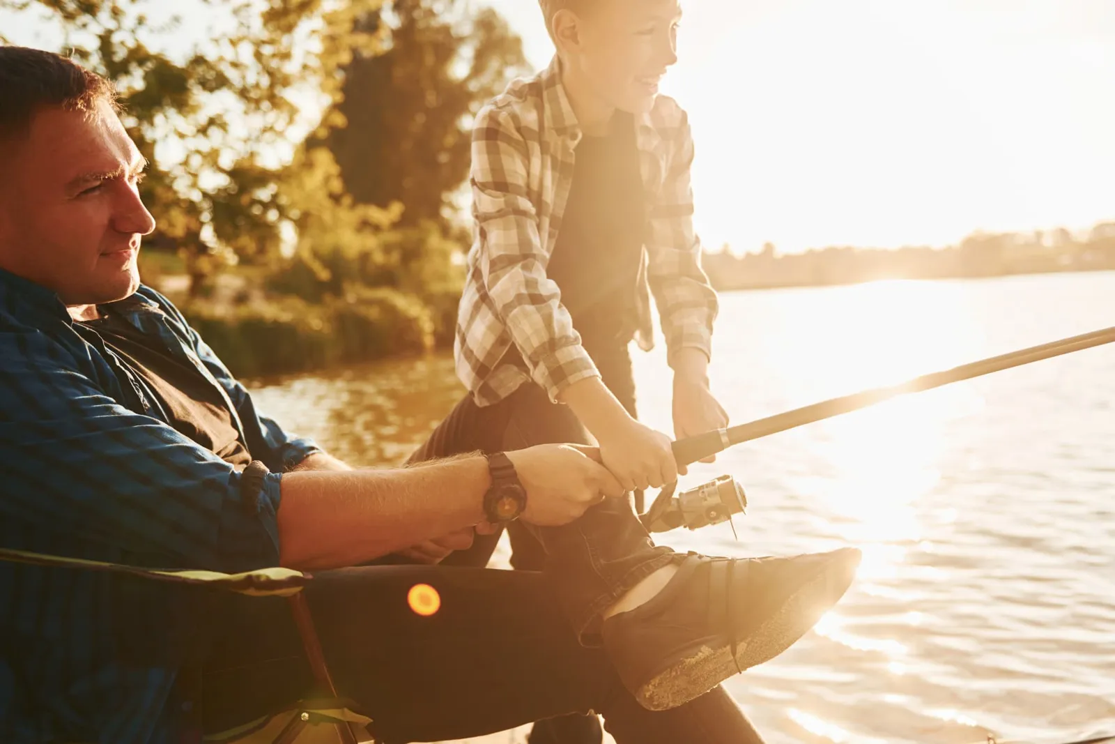 Parent and child fishing together from a sunny lakeshore